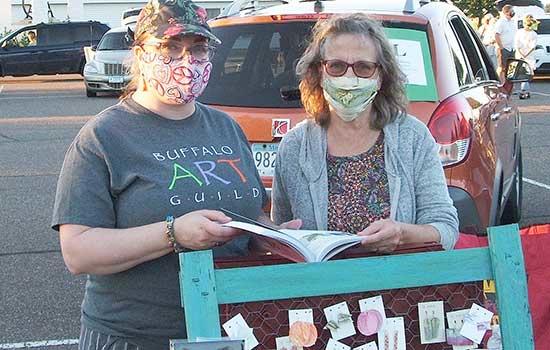 Robin Moravec, left, showed an attendee, right, her artwork.