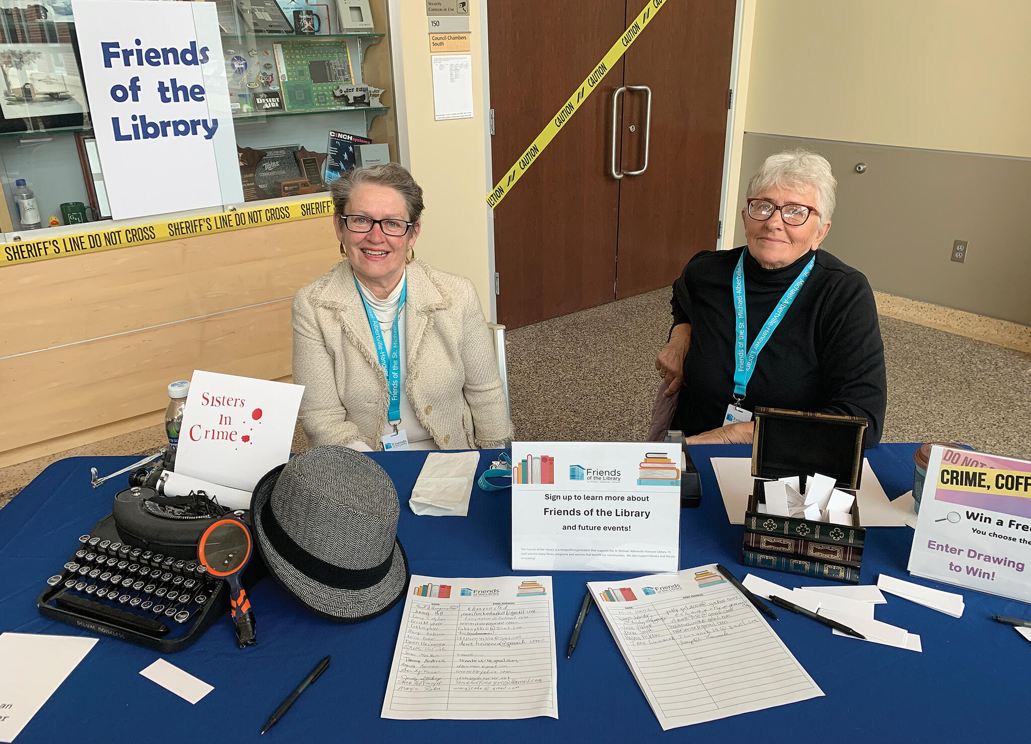 Kathy Mischke (left) and Jean Ellingson (right) of the Friends of the Library - St. Michael, Albertville, and Hanover, welcomed mystery and crime fiction readers to the book festival event on April 20.
