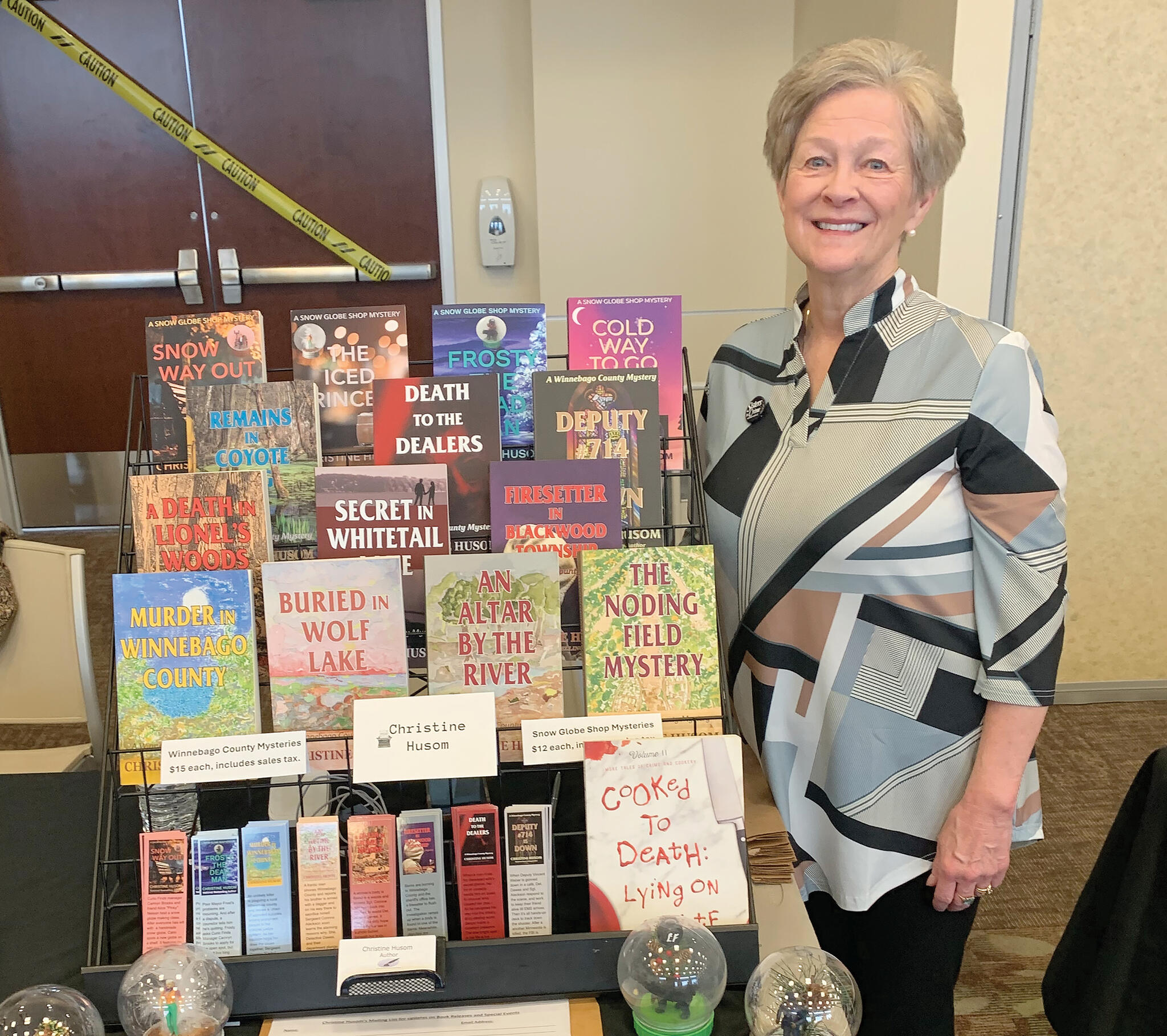Buffalo resident and author, Christine Husom, stands next to a display of her novels. Book festival attendees had a chance to meet and talk with several authors and members of Sisters in Crime.