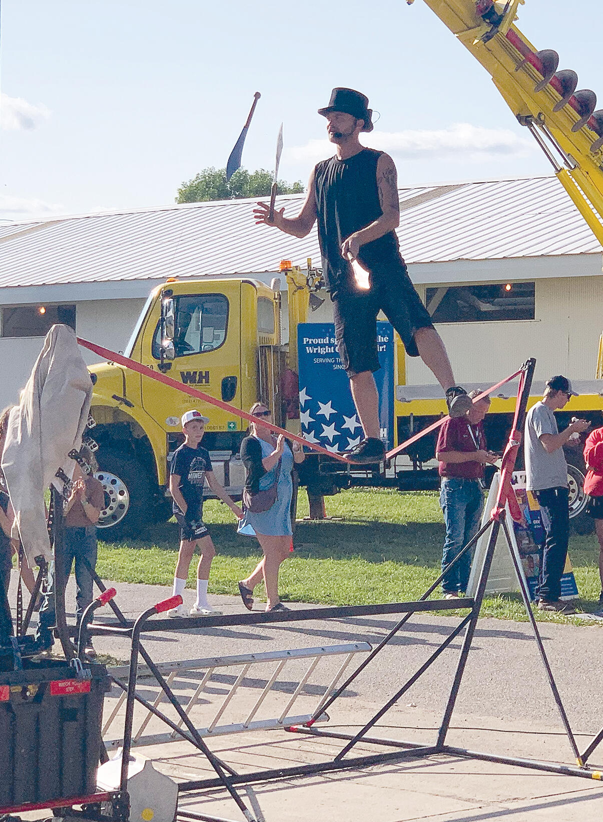 A performer with Dangerous Feats of Comedy juggled three large knives while balancing on a slackline.