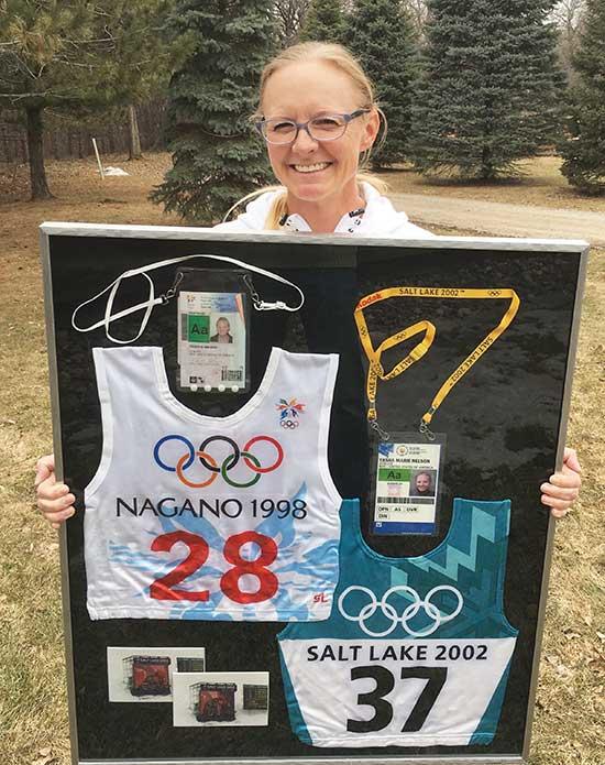 Tasha Nelson poses with her two Olympic bibs, as well as her credentials, she wore while competing in the 1998 Olympics in Nagano, Japan, and 2002 Salt Lake City, Utah. (Submitted photo)